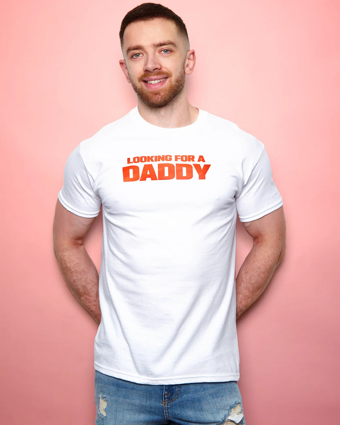 Man wearing a white t-shirt with 'Looking for a Daddy' text on a pink background