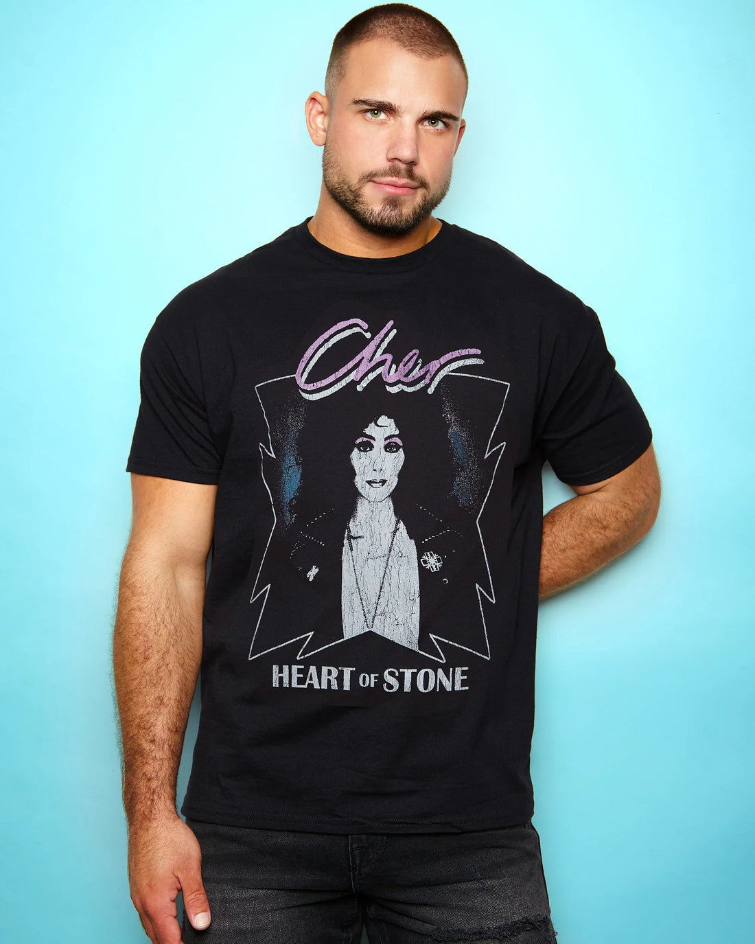 Man wearing a black t-shirt with Cher Heart of stone 1989 tour design against a light blue background