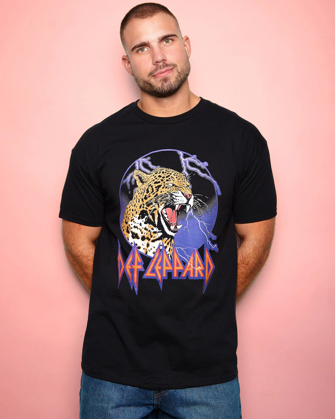 Man wearing a black t-shirt with a leopard graphic and 'Def Leppard' text on a pink background