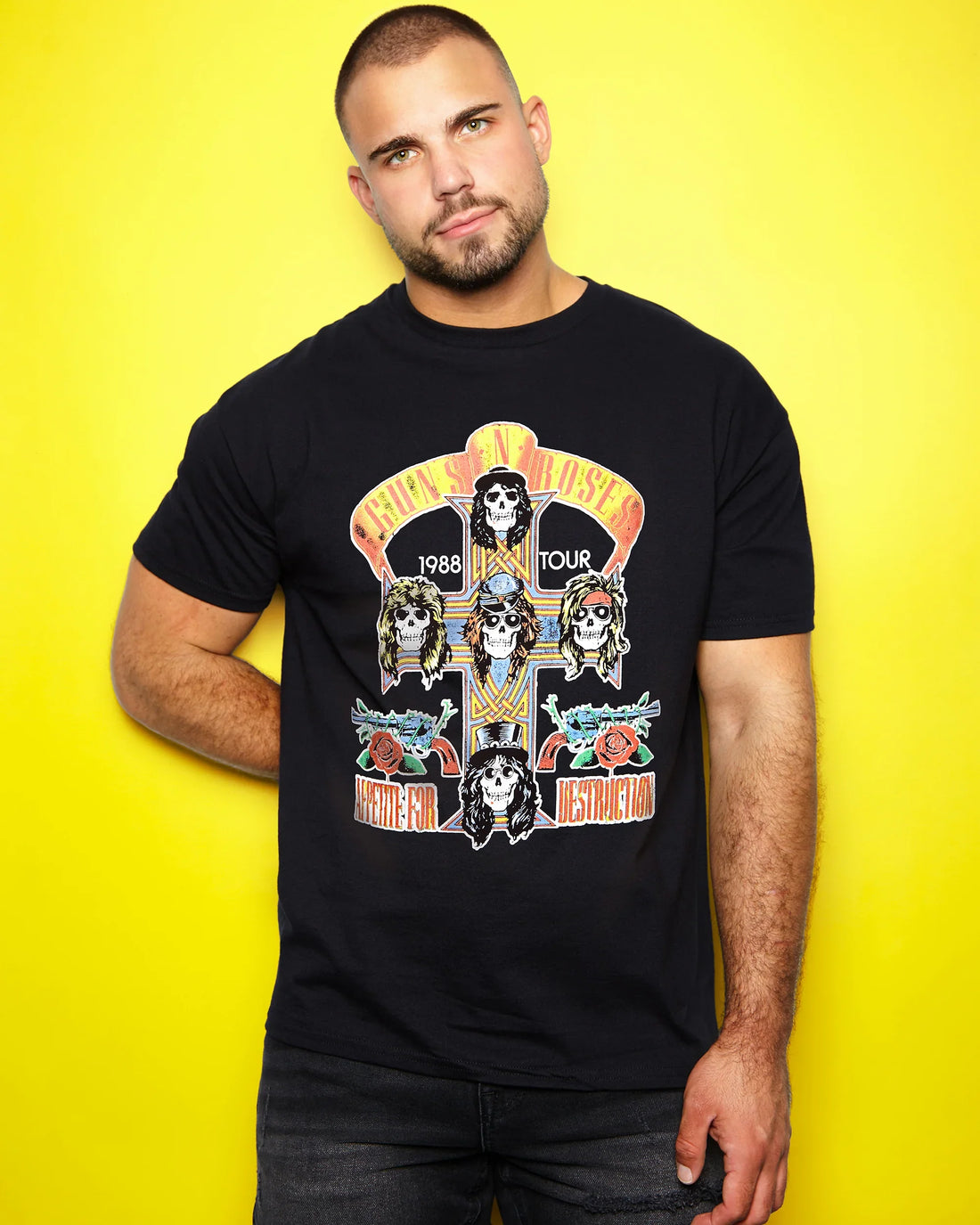 Man wearing a black t-shirt with Guns N' Rose 1988 tour graphic against a yellow background