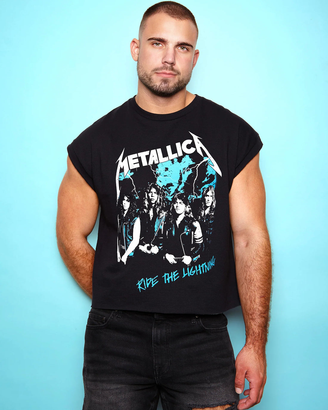 Man wearing a black sleeveless shirt with Metallica 1985 Ride the lightning tour graphic design against a light blue background