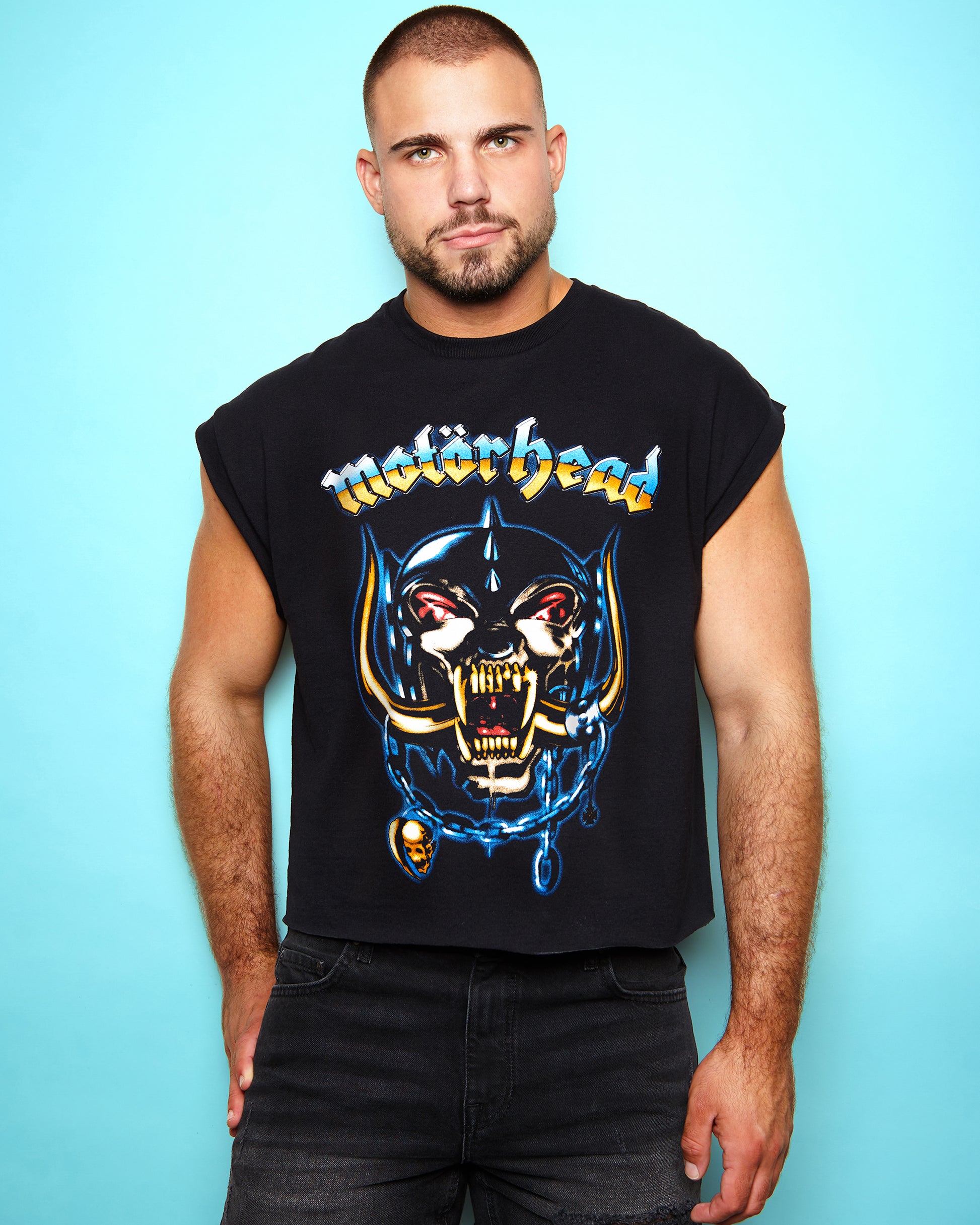 Man wearing a black sleeveless shirt with a graphic design and 'Motorhead Airbrush' text against a light blue background