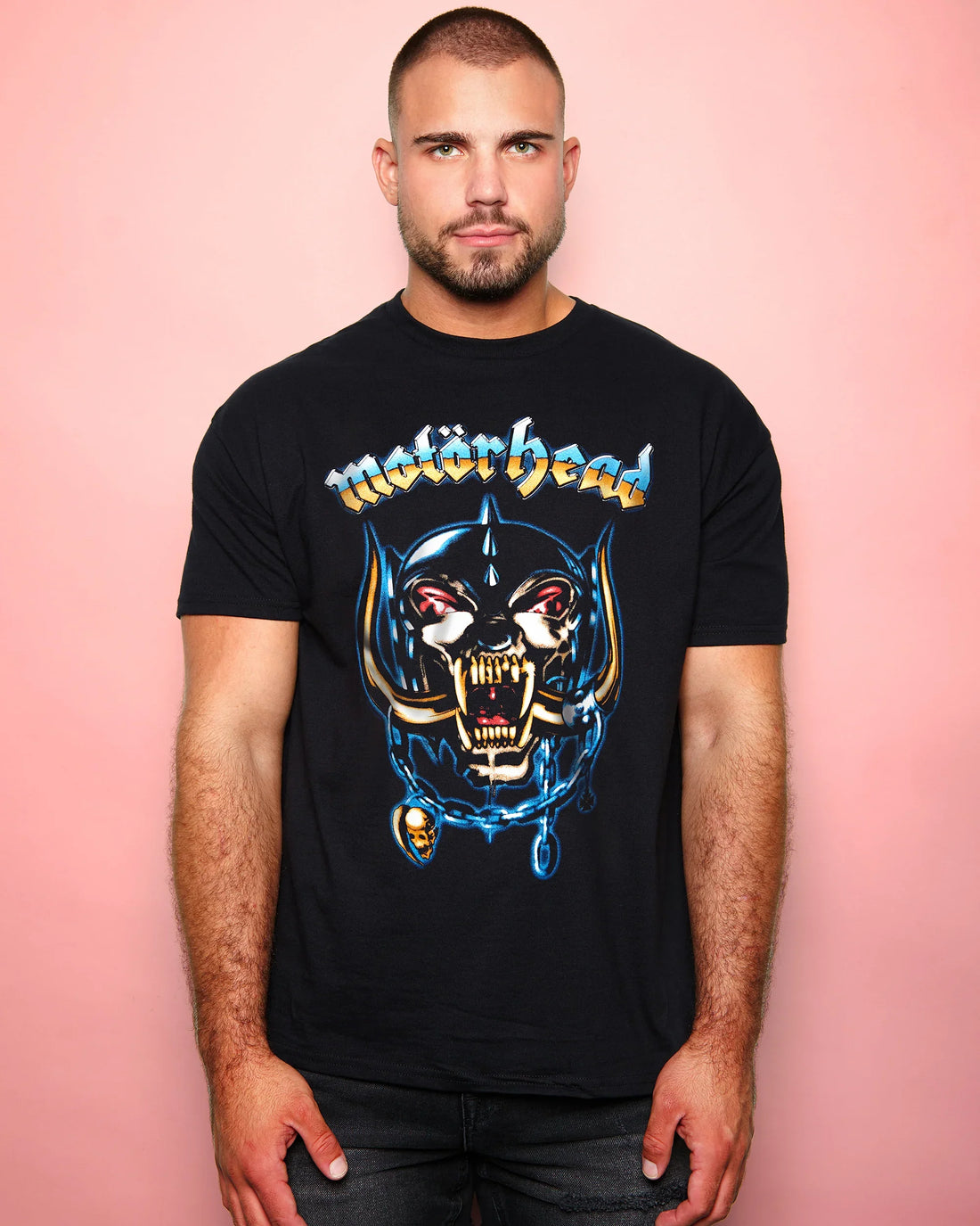 Man wearing a black t-shirt with a graphic design and 'Motorhead Airbrush' text against a pink background