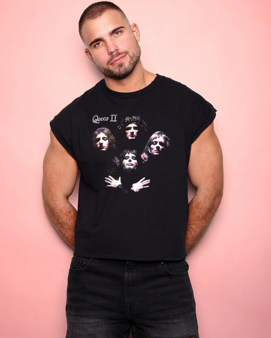 Man wearing a black sleeveless shirt Queen Bohemian Rhapsody graphic on a pink background
